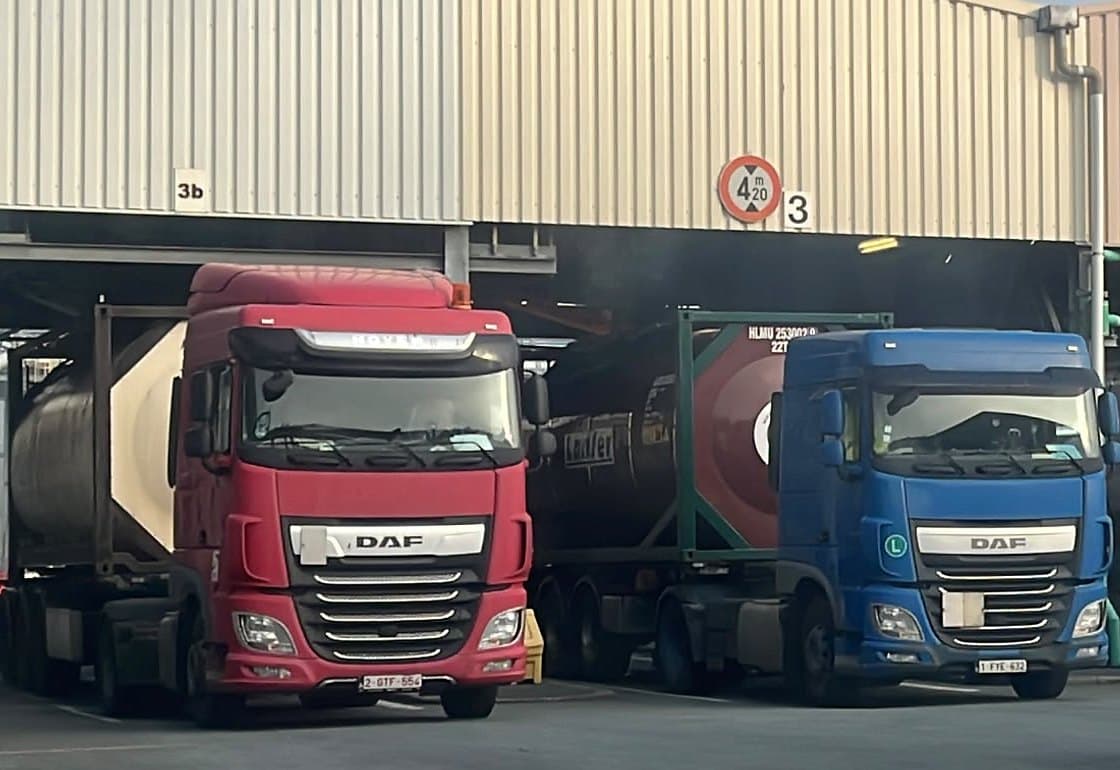 Twee trekkers van HK Trans met tankcontainers onder de luifel van een laadstation
